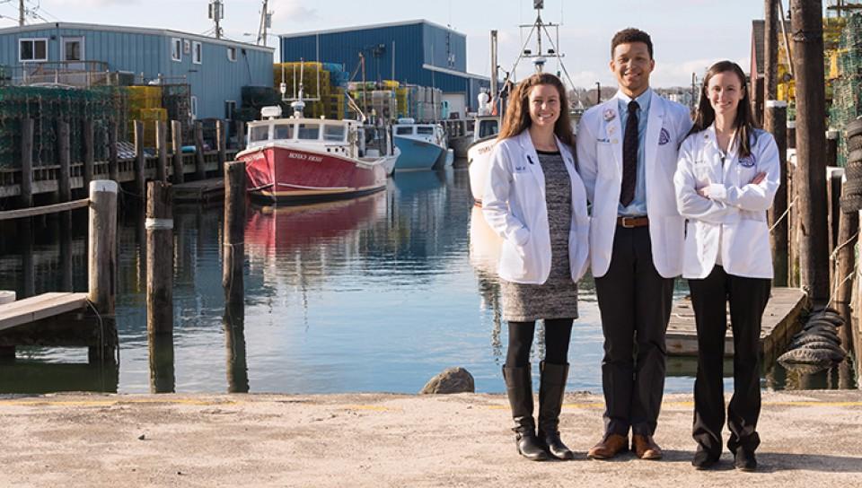 Three graduate 学生 standing by the Widgery Wharf in Portland, Maine